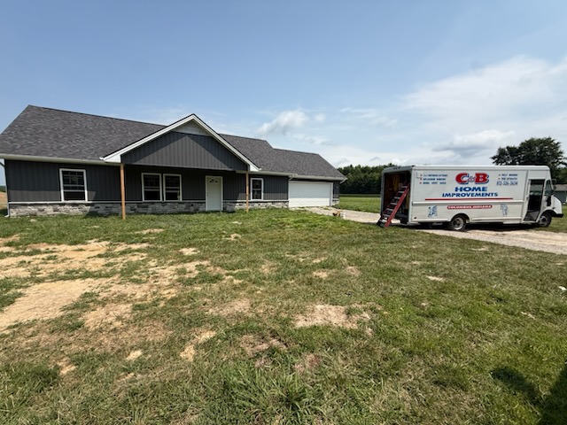 After - completed dark gray siding front view with truck